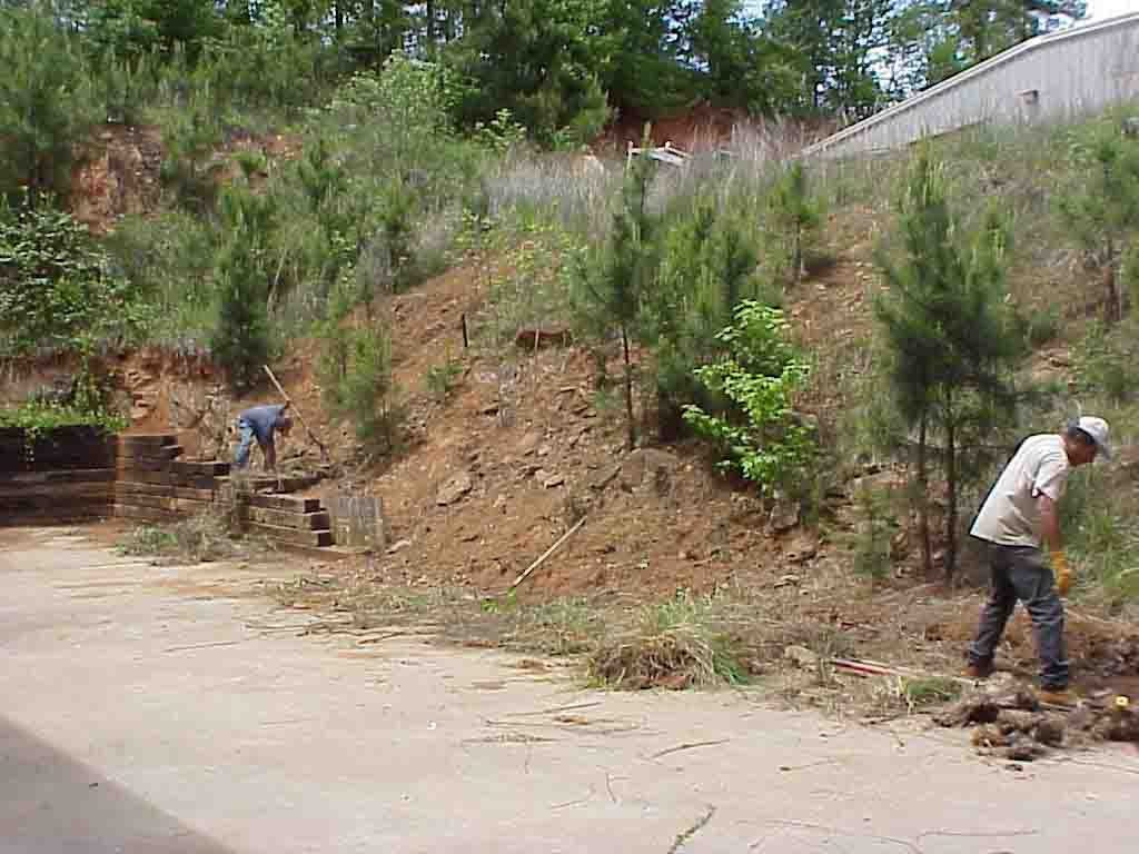 Workers preparing a steep bare slope before hydroseeding